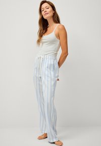Lichtblauwe en witte gestreepte pyjamabroek met een trekkoord in de taille, gecombineerd met een aansluitend wit tanktopje met kantafwerking.
