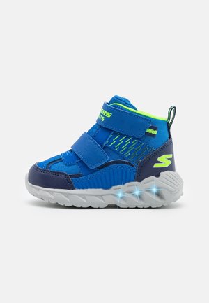 Baskets pour enfants bleu et vert néon avec deux bandes velcro et semelle lumineuse sur fond blanc.