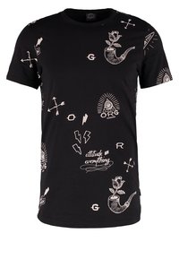Camiseta negra con diseños en estilo tatuaje en blanco que incluyen tubos con rosas, flechas, rayos y la frase "la actitud lo es todo".