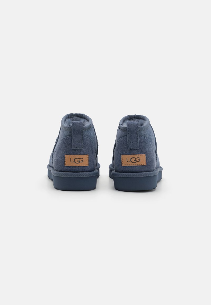 Navyblaue Wildleder-Stiefeletten mit weicher Textur, ausgestattet mit einem verstärkten Absatz und einem gefütterten Lederetikett auf der Rückseite. Gummisohle für besseren Halt.