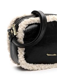 Borsa a tracolla in pelle nera con rifiniture bianche pelose, dotata di una cerniera e accessori in oro. Forma arrotondata con un manico corto per il trasporto.