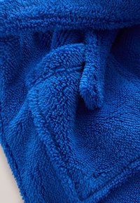 Coperta morbida in pile blu con una superficie soffice e strutturata. Presenta un aspetto stropicciato, che mette in risalto una saturazione profonda del colore e un aspetto accogliente.