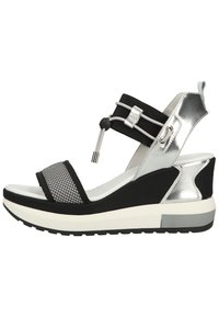 Black and silver sandal with mesh front strap, elastic ankle band, and chunky white midsole. Textured materials provide contrast and support.