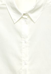 Weißes Hemd mit knöpfbarem Kragen, bestehend aus einem glatten Stoff und sechs Knöpfen entlang der Vorderseite. Sauberes, einfaches Design.