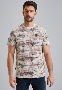 T-shirt i creme med et geometrisk mønster i rød og sort. Har en rund halsudskæring og et lille mærke på brystet.