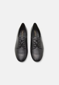 Chaussures en cuir noir avec une texture lisse, à lacets et à bout rond. Présentant des accents décoratifs minimaux.