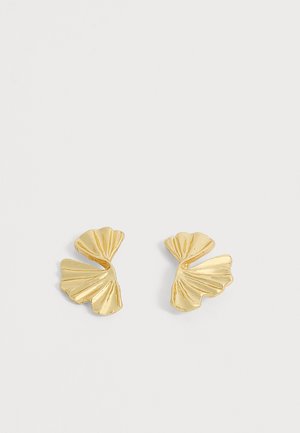 Paire de boucles d'oreilles dorées en forme d'éventail ou de feuille abstraite avec des surfaces texturées et courbées sur fond blanc.