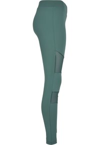 Leggings verdi a vita alta con accenti in rete sui lati, texture liscia e design aderente. Adatti per l'abbigliamento sportivo.