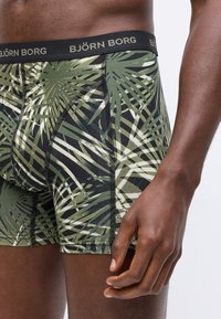 Zöld és fekete mintás boxeralsó, pálmalevél mintázattal, rugalmas derékrésszel, amelyen a "BJÖRN BORG" felirat látható, és jól látható varrási részletek.