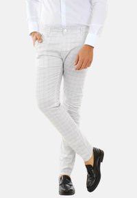 Pantaloni grigi chiari a quadri con una vestibilità slim, realizzati in un tessuto testurizzato, caratterizzati da una chiusura con bottone e tasche laterali, abbinati a mocassini neri.