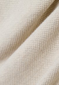 Lichtbeige textiel met een geweven patroon, met een zachte, licht fuzzy oppervlak en een subtiele glans.