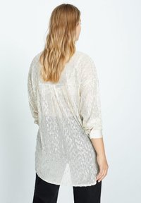 Transparante, lange mouwen, gebloemde blouse in iriserend zilver, met een losse pasvorm en een ronde zoom met een knoopsluiting aan de manchetten. Achteraanzicht weergegeven.