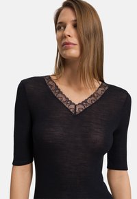 Top corto a maniche corte nero a costine con scollatura a V e un bordo in pizzo intricatamente decorato attorno al collo in un delicato motivo floreale.