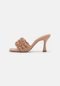Beige high-heeled slide sandal featuring a woven knot design on the upper and a tapered stiletto heel. Smooth texture and square toe shape.