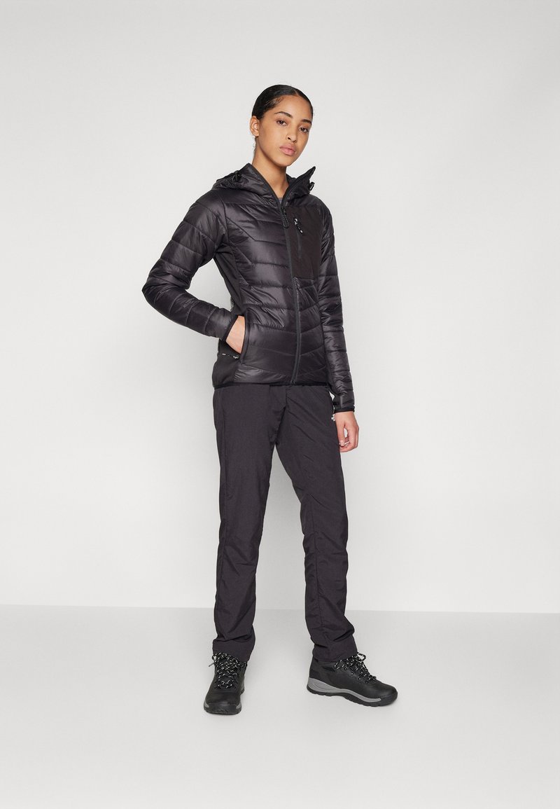 Schwarze Daunenjacke mit Kapuze, Reißverschluss vorne und Taschen. Getragen mit schwarzen Hosen und robusten Stiefeln, geeignet für Outdoor-Bedingungen.