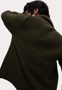 Dunkelgrüner gerippter Pullover mit lockerer Passform, der aus strukturierter Stoff besteht und über versetzte Schultern verfügt, was ihm ein weiches, gemütliches Aussehen verleiht.