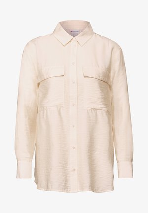 Krémová dlouhá košile s rukávy vyrobená z hladké tkaniny, s límcem, zapínáním na knoflíky vpředu a dvěma kapsami na hrudi.