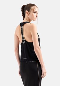 Top atletico senza maniche di colore nero con schiena alta, dotato di spalline con logo e vestibilità comoda, realizzato in tessuto leggero e morbido.