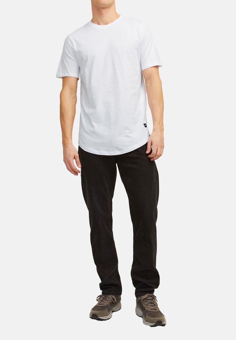 Witte katoenen t-shirt met korte mouwen en een ronde hals, gecombineerd met zwarte ribfluwelen broek en grijze sneakers. Eenvoudige, ontspannen pasvorm.