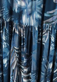Țesătură cu model floral în nuanțe de albastru, cu secțiuni drapate. Textura pare netedă, cu un ușor luciu, creând adâncime în design.