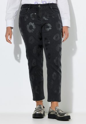 Sorte jeans med høj talje med subtilt skinnende blomsterprint, båret med metallic sølv loafers og en hvid langærmet skjorte.