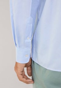 Lichtblauwe gestreepte shirt met knoopmanchetten, met een getailleerde pasvorm, van katoen en met een gladde textuur. Zichtbare kraag en zoom van het shirt.