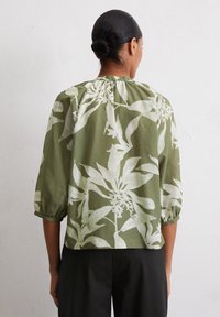 Green leaf-patterned blouse with three-quarter puff sleeves, soft fabric, gathered neckline, and cropped hem, shown from the back.