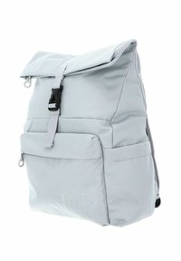 Sac à dos gris clair avec un design à ouverture roulante, comprenant une poche frontale zippée et une fermeture à boucle noire. Tissu texturé avec un détail de logo.