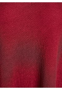 Tekstūrota sarkanā auduma ar smalku rakstu, kas izceļas ar maigu apdari. Materiāls izskatās viegls un austs ar nelielu spīdumu.