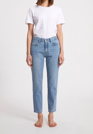 Jasnoniebieskie, wysokiej talii dżinsy o prostym kroju, z przednimi kieszeniami, zapięciem na guzik i minimalnym wyblaknięciem. Połączone z gładką białą koszulką.