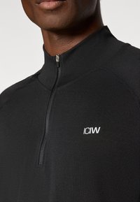 Μαύρο αθλητικό τοπ με φερμουάρ, κατασκευασμένο από λείο ύφασμα. Διαθέτει ψηλό γιακά και μικρ ό λευκό λογότυπο "ICIW" στο εμπρόσθιο μέρος.