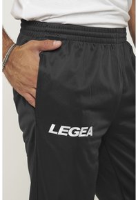 Zwarte sportbroek met een gestructureerde afwerking, voorzien van een elastische tailleband en het "LEGEA"-logo in het wit aan de linkerzijde.