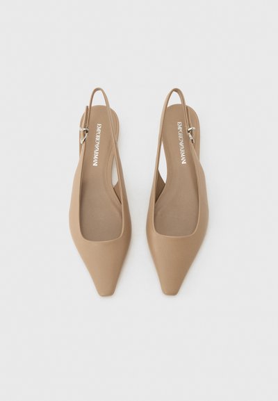 Μπεζ μπαλαρίνες με μυτερή μύτη, λουράκια που αγκαλιάζουν τον αστράγαλο και ρυθμιζόμενα λουράκια, με εσωτερικές σόλες με σήμανση, απεικονισμένες σε λευκό φόντο.