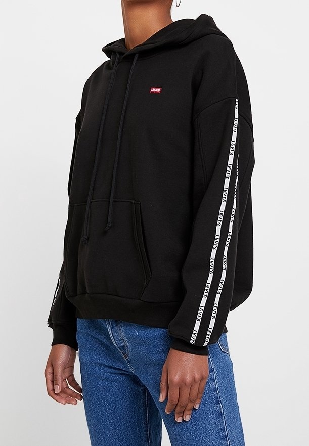 Sudadera negra con capucha y cordones, con cinta logo blanca a lo largo de las mangas. Tela suave, bolsillo canguro en el frente y corte relajado.