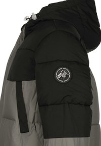 Puffjakke i svart og grå fargekombinasjon, med en rund hette, teksturert overflate, og et sirkulært logo-patch på ermet.