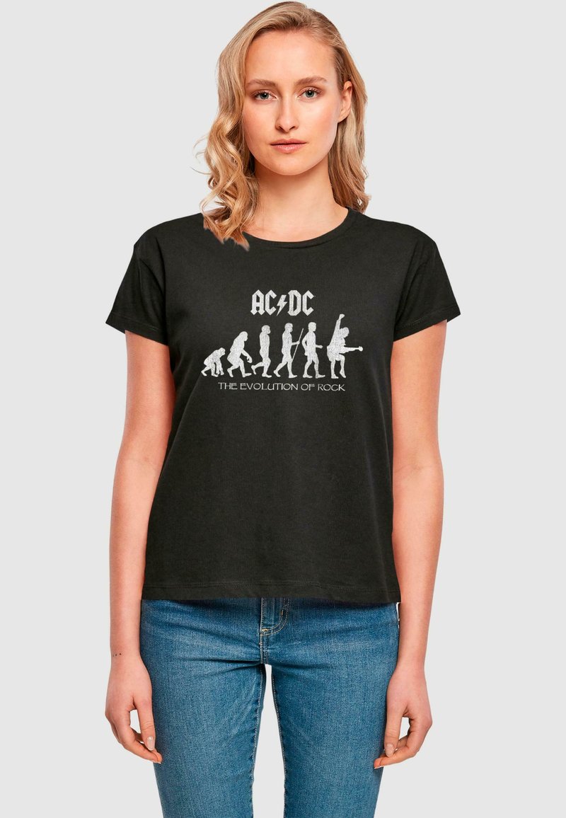 Schwarz kurzärmliges T-Shirt mit einem grafischen Design, das den Text "AC/DC" und Silhouetten zeigt, die die Evolution der Rockmusik darstellen.