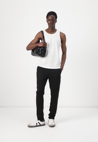 Geantă neagră cu textură stratificată, tricou alb cu dungi, pantaloni negri și teniși gri cu dungi negre și albe. Design minimalist.