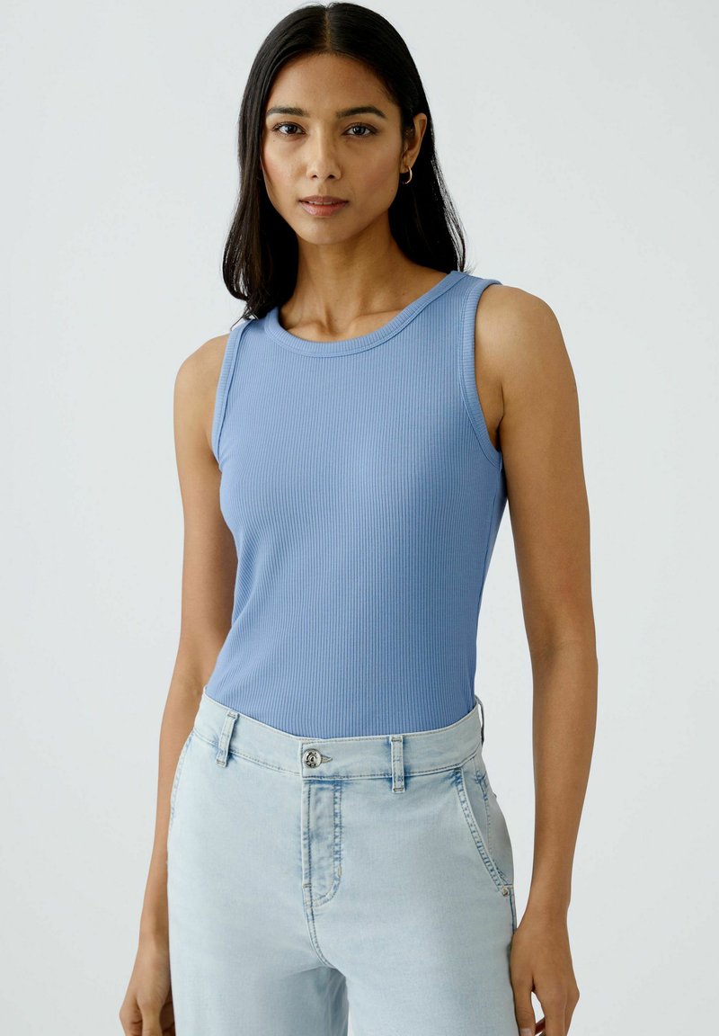 Light blue ribbed tank top with a round neckline, paired with light wash denim jeans. Features fitted design and minimal seams.