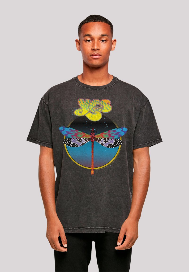 Black oversized graphic t-shirt featuring a multicolored dragonfly design with a circular background; cotton material, crew neck, short sleeves.