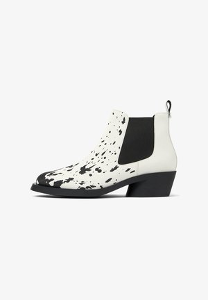 White leather Chelsea boots featuring a black splatter pattern, elastic side panels, and a black block heel.