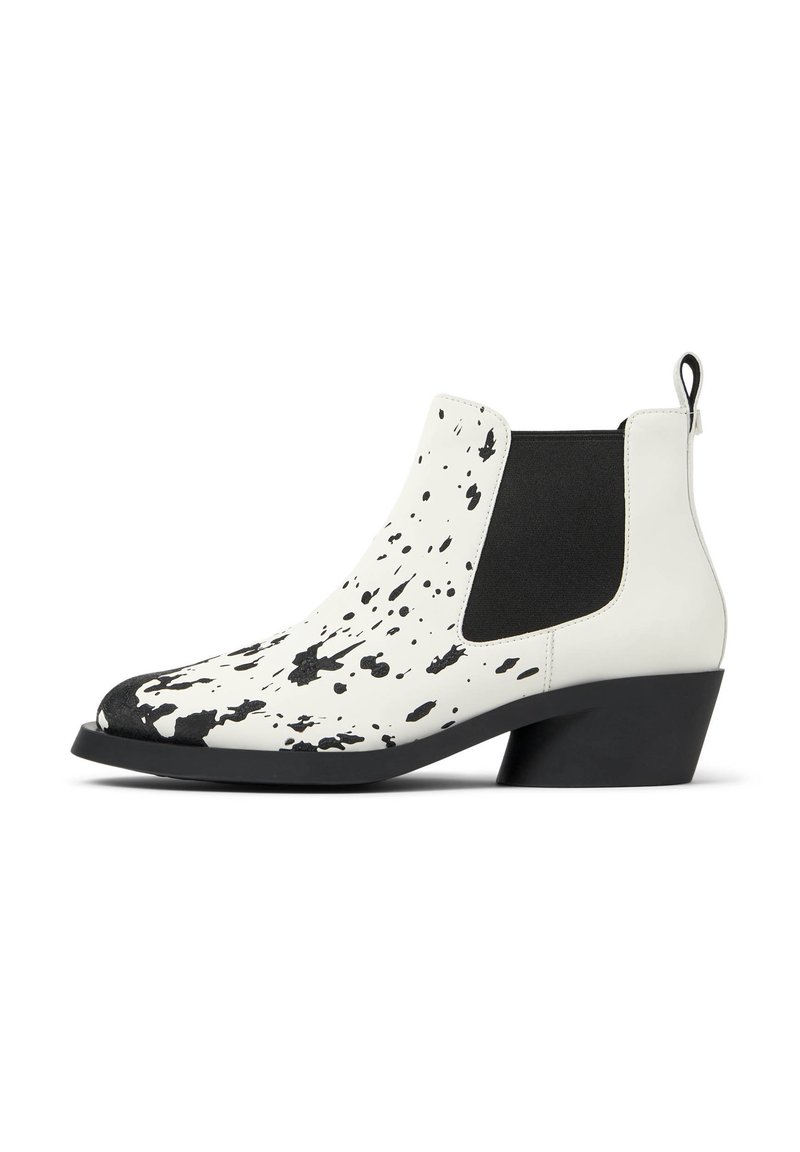 Botas Chelsea de cuero blanco con un patrón de manchas negras, paneles laterales elásticos y un tacón cuadrado negro.