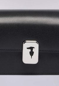 Černé kožené psaníčko s texturovaným povrchem, vybavené stříbrnou sponou s obrysem psa. Čisté linie a minimalistický design.