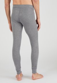 Leggings grises hechos de un tejido suave y elástico. Presentan un ajuste ceñido y una cinturilla elástica, con una textura lisa y sin patrones visibles.