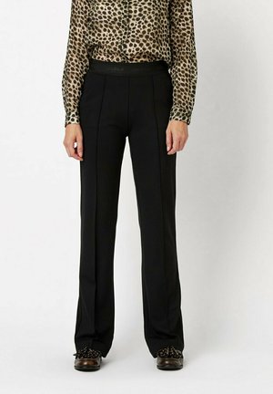 Schwarze Hosen mit geradem Schnitt, aus glattem Stoff und einem breiten, gewebten Bund. Kombiniert mit einer transparenten Bluse im Leopardenmuster.