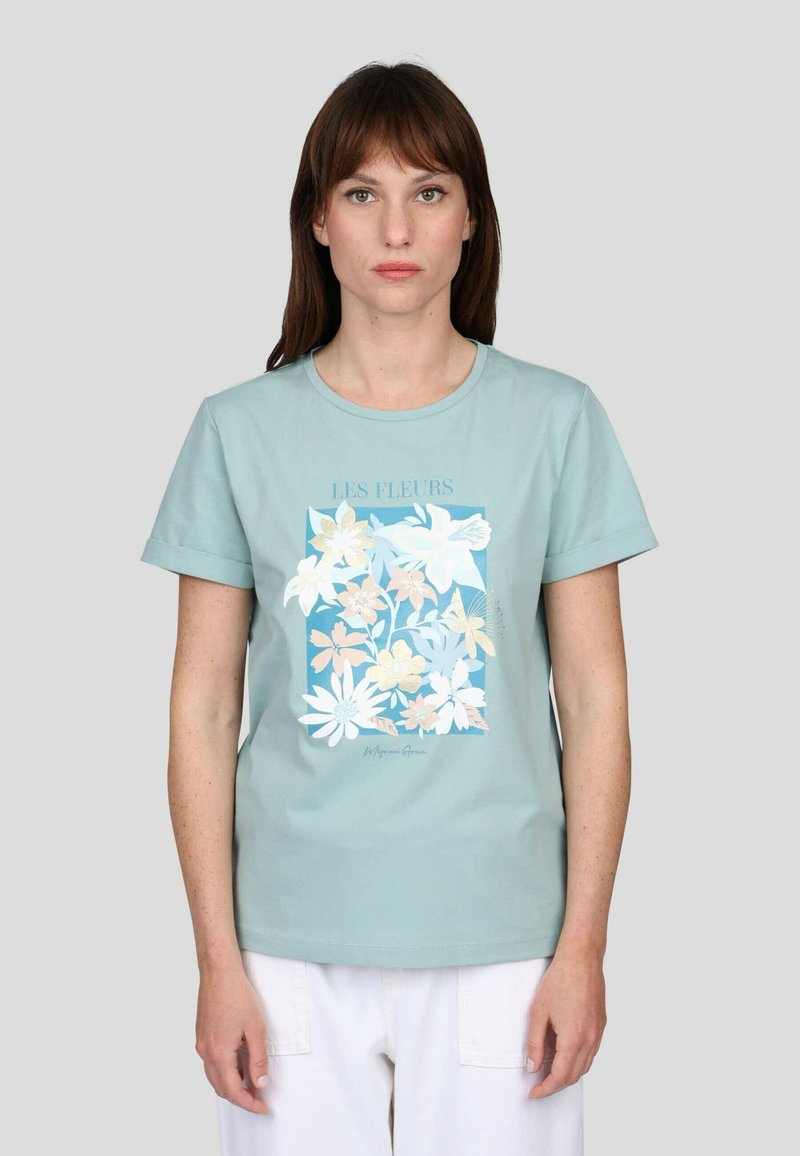 T-shirt en coton bleu-vert clair featuring un imprimé floral en blanc et en teintes pastel, avec des manches courtes et un col rond. Accentué par "LES FLEURS."