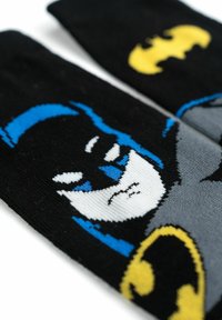 Calze nere con un motivo grafico di Batman in grigio e blu, con un logo di Batman giallo, design lavorato a maglia e texture morbida.