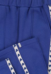 Blauwe stoffen broek met een zachte textuur, voorzien van een geplooide tailleband en zijzakken, accentueert met een hartjespatroon tape.