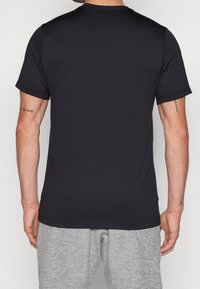 Černé tričko s krátkým rukávem vyrobené z hladkého materiálu. Má zaoblený výstřih a jednoduchý design. Pohled ze zadu nezobrazuje žádné další vzory.