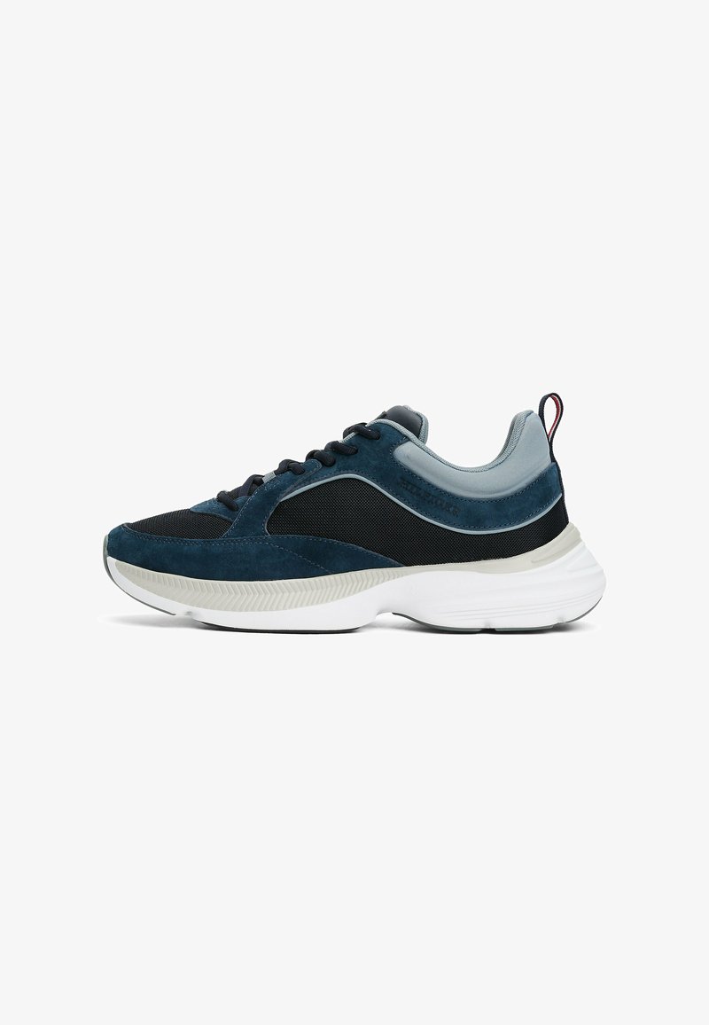 Sneaker da uomo in camoscio blu navy e nero con dettagli in rete, suola bianca, punta rotonda e lacci piatti. Tassello sul retro per facilitarne l'indossamento.