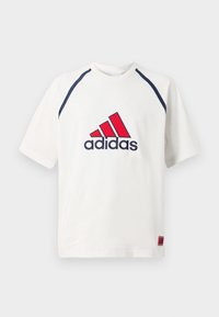 Camiseta blanca de manga corta con acentos en azul marino, que presenta un logo de Adidas en rojo y azul en la parte frontal y una pequeña etiqueta de marca en la parte inferior.